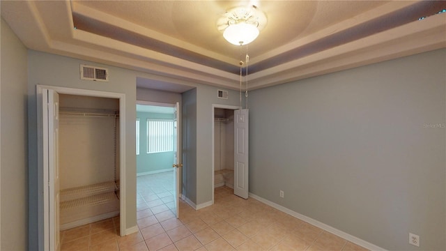 unfurnished bedroom with a raised ceiling, visible vents, baseboards, and light tile patterned floors