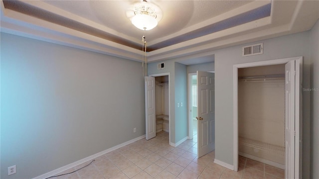 unfurnished bedroom featuring light tile patterned floors, a raised ceiling, visible vents, and baseboards