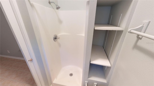 full bathroom with a shower stall, baseboards, and tile patterned flooring