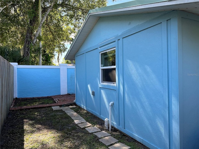 view of side of property with an outbuilding, a fenced backyard, and stucco siding