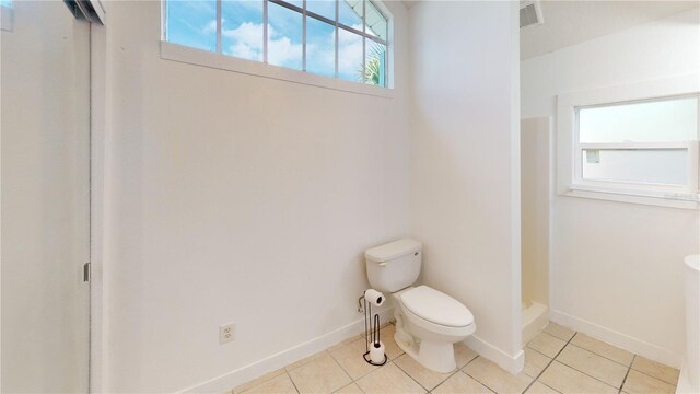 bathroom with a healthy amount of sunlight, tile patterned flooring, and toilet