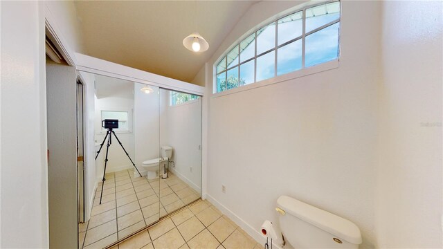 bathroom featuring tile patterned flooring, baseboards, lofted ceiling, and toilet