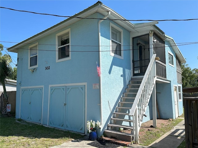 view of property exterior with stairs, fence, and stucco siding