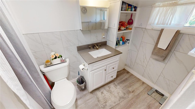 bathroom featuring toilet, wood finished floors, tile walls, and vanity