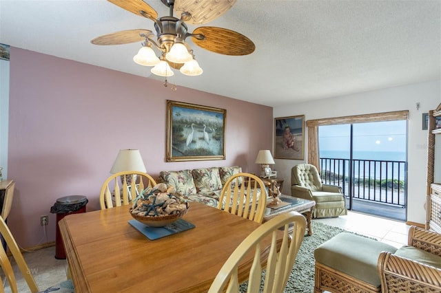 dining space with a water view, ceiling fan, and a textured ceiling