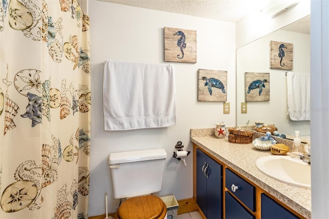 bathroom with toilet, vanity, and a textured ceiling