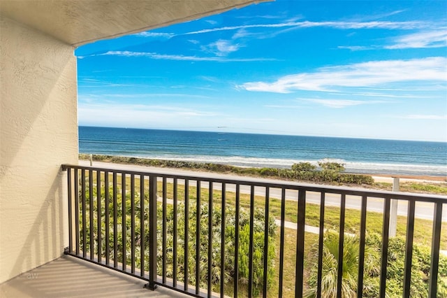 balcony with a water view and a view of the beach