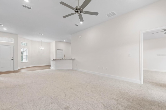 unfurnished living room featuring light colored carpet and ceiling fan with notable chandelier