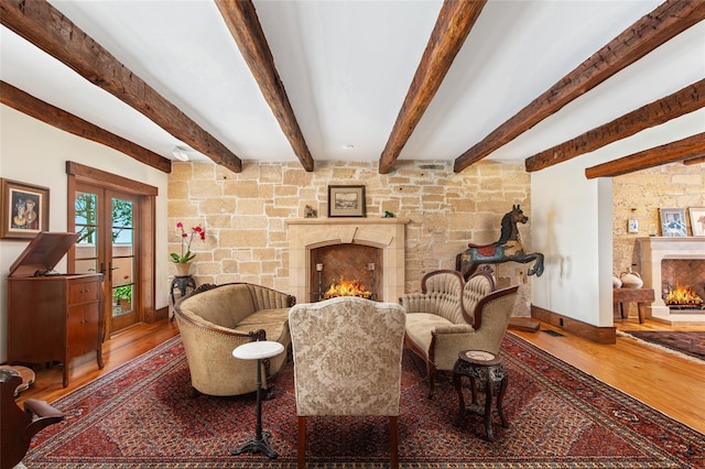 sitting room featuring french doors, a fireplace, hardwood / wood-style floors, and beam ceiling