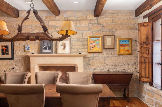 sitting room with beamed ceiling, wood-type flooring, and a fireplace