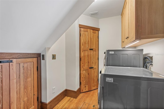 washroom featuring cabinets, independent washer and dryer, and light hardwood / wood-style floors