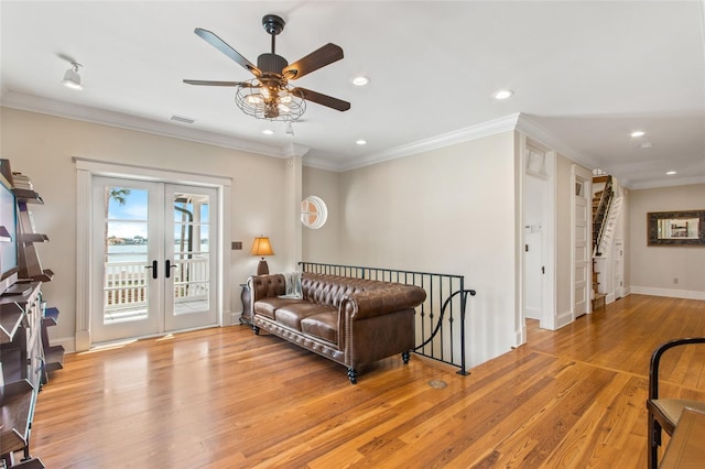 living room featuring french doors, crown molding, and light hardwood / wood-style floors