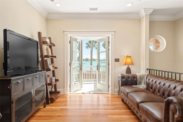 interior space with crown molding, a water view, and light wood-type flooring