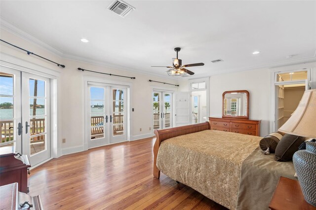 bedroom with french doors, a water view, crown molding, light hardwood / wood-style flooring, and access to outside