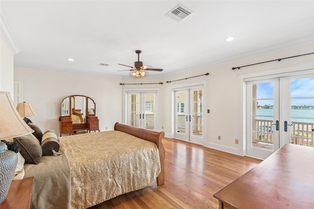 bedroom featuring light hardwood / wood-style flooring, access to exterior, a water view, ornamental molding, and french doors