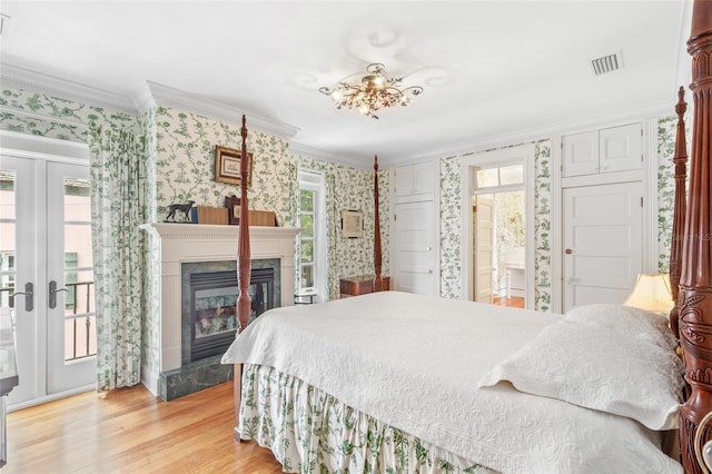 bedroom with french doors, light hardwood / wood-style flooring, ornamental molding, a high end fireplace, and access to exterior