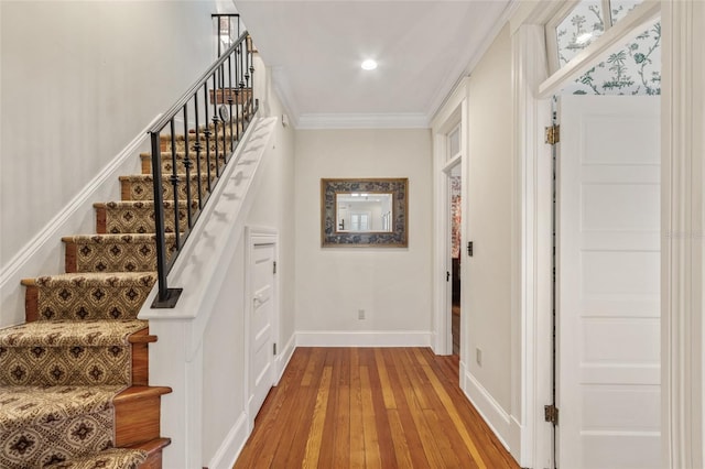 stairway with hardwood / wood-style flooring and ornamental molding