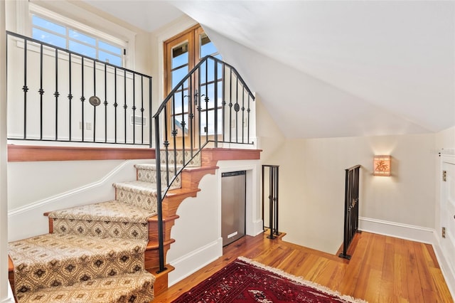 staircase featuring wood-type flooring and vaulted ceiling