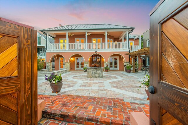 view of front of property featuring french doors, a balcony, a pergola, ceiling fan, and a patio