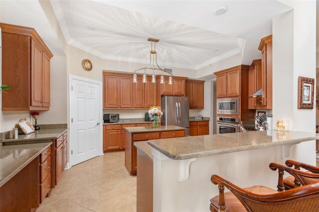 kitchen with light stone counters, hanging light fixtures, appliances with stainless steel finishes, and a breakfast bar area