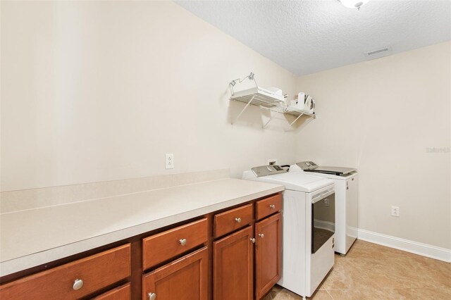 laundry room featuring a textured ceiling, light tile patterned floors, and washer and dryer