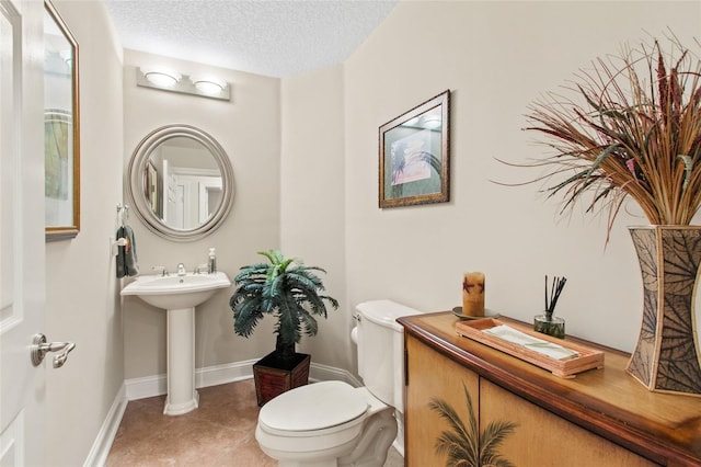 bathroom with toilet, sink, tile patterned floors, and a textured ceiling