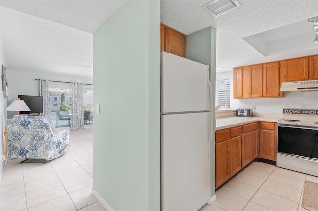 kitchen featuring light tile patterned floors, white appliances, and a textured ceiling