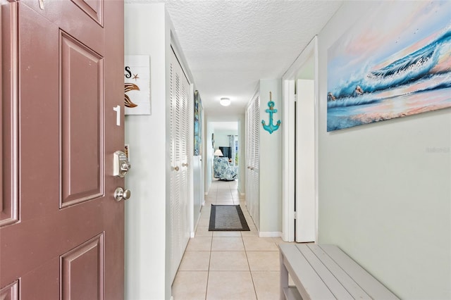 corridor with a textured ceiling and light tile patterned floors