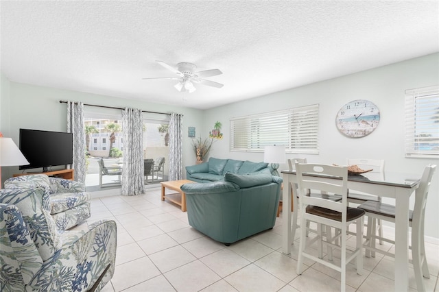 living room featuring ceiling fan, light tile patterned floors, and a textured ceiling