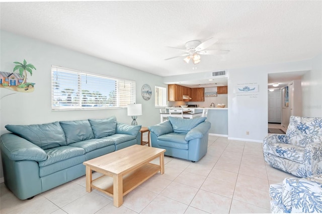 living room with ceiling fan, a textured ceiling, and light tile patterned floors