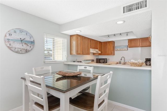 kitchen with sink, a textured ceiling, light tile patterned floors, and rail lighting