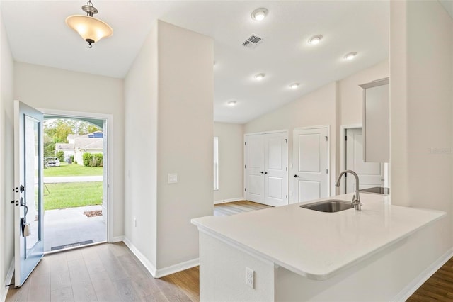 66 Ryland Dr, Palm Coast, FL 32164 - kitchen with kitchen peninsula, sink, light hardwood / wood-style floors, and lofted ceiling