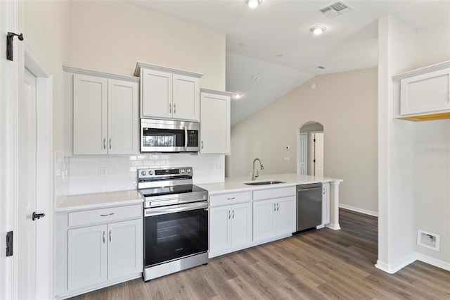 66 Ryland Dr, Palm Coast, FL 32164 - kitchen featuring white cabinets, sink, vaulted ceiling, light hardwood / wood-style floors, and stainless steel appliances