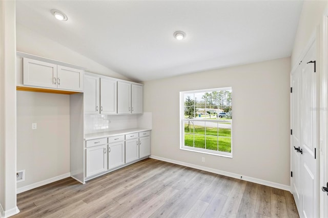 66 Ryland Dr, Palm Coast, FL 32164 - kitchen featuring white cabinets, light wood-type flooring, and vaulted ceiling