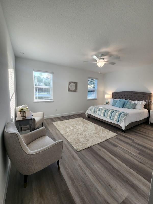 bedroom featuring multiple windows, a textured ceiling, ceiling fan, and dark hardwood / wood-style floors