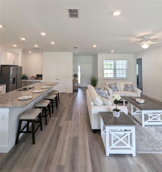 living room with hardwood / wood-style floors, ceiling fan, and sink