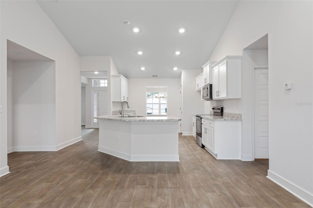 kitchen with light stone counters, white cabinets, and appliances with stainless steel finishes