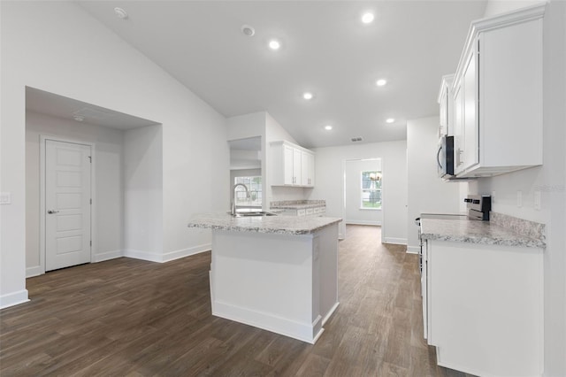 kitchen with lofted ceiling, sink, light stone countertops, dark wood-type flooring, and white cabinets