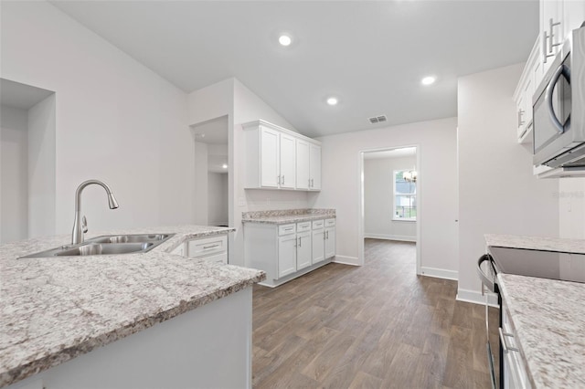 kitchen featuring sink, white cabinetry, dark wood-type flooring, appliances with stainless steel finishes, and light stone counters