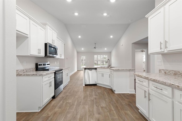 kitchen with vaulted ceiling, appliances with stainless steel finishes, and white cabinetry