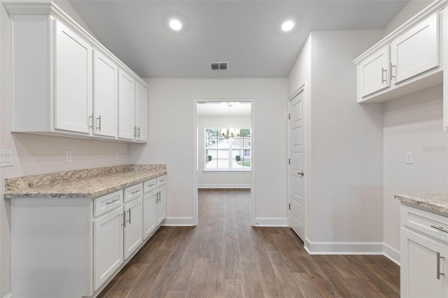 kitchen featuring white cabinetry, dark hardwood / wood-style flooring, light stone counters, and a chandelier