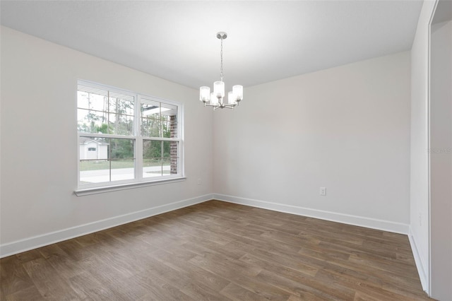 empty room with dark wood-type flooring and a notable chandelier