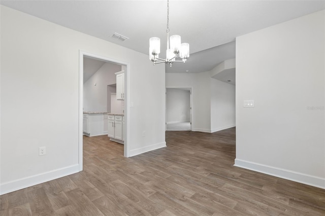 unfurnished dining area featuring wood-type flooring and a chandelier