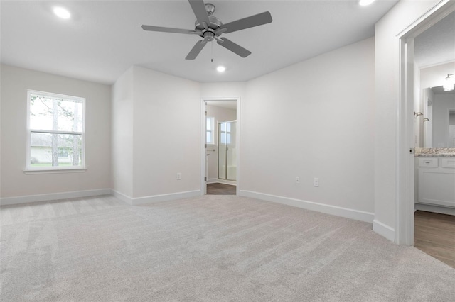 unfurnished bedroom with ensuite bathroom, ceiling fan, and light carpet