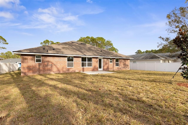 rear view of house featuring a lawn and a patio