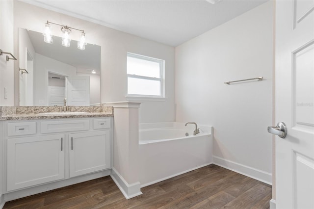 full bathroom featuring wood finished floors, a bath, vanity, and baseboards