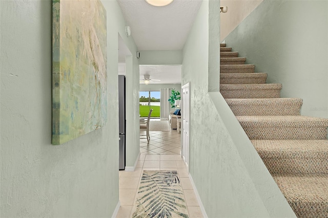 stairway featuring ceiling fan and tile patterned flooring