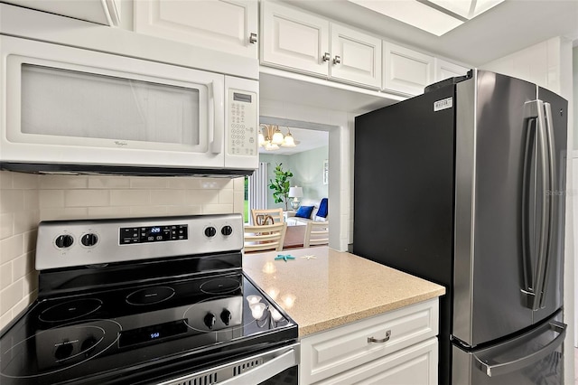 kitchen with stainless steel appliances, decorative backsplash, and white cabinets