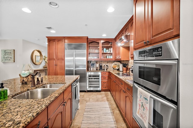 kitchen featuring beverage cooler, stainless steel appliances, decorative backsplash, sink, and light stone counters