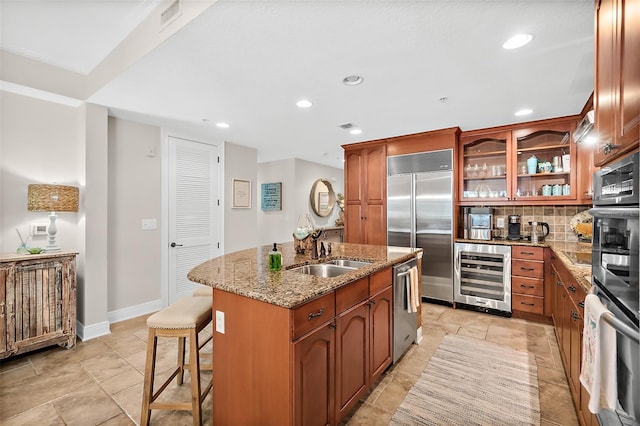 kitchen featuring stainless steel appliances, wine cooler, sink, a center island with sink, and a breakfast bar area